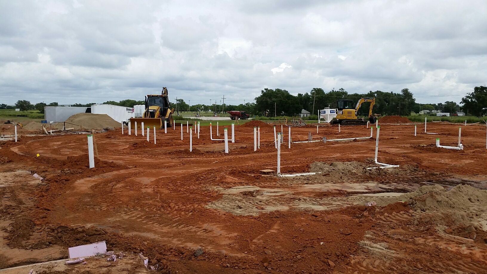 A construction site with pipes and a bulldozer in the background.