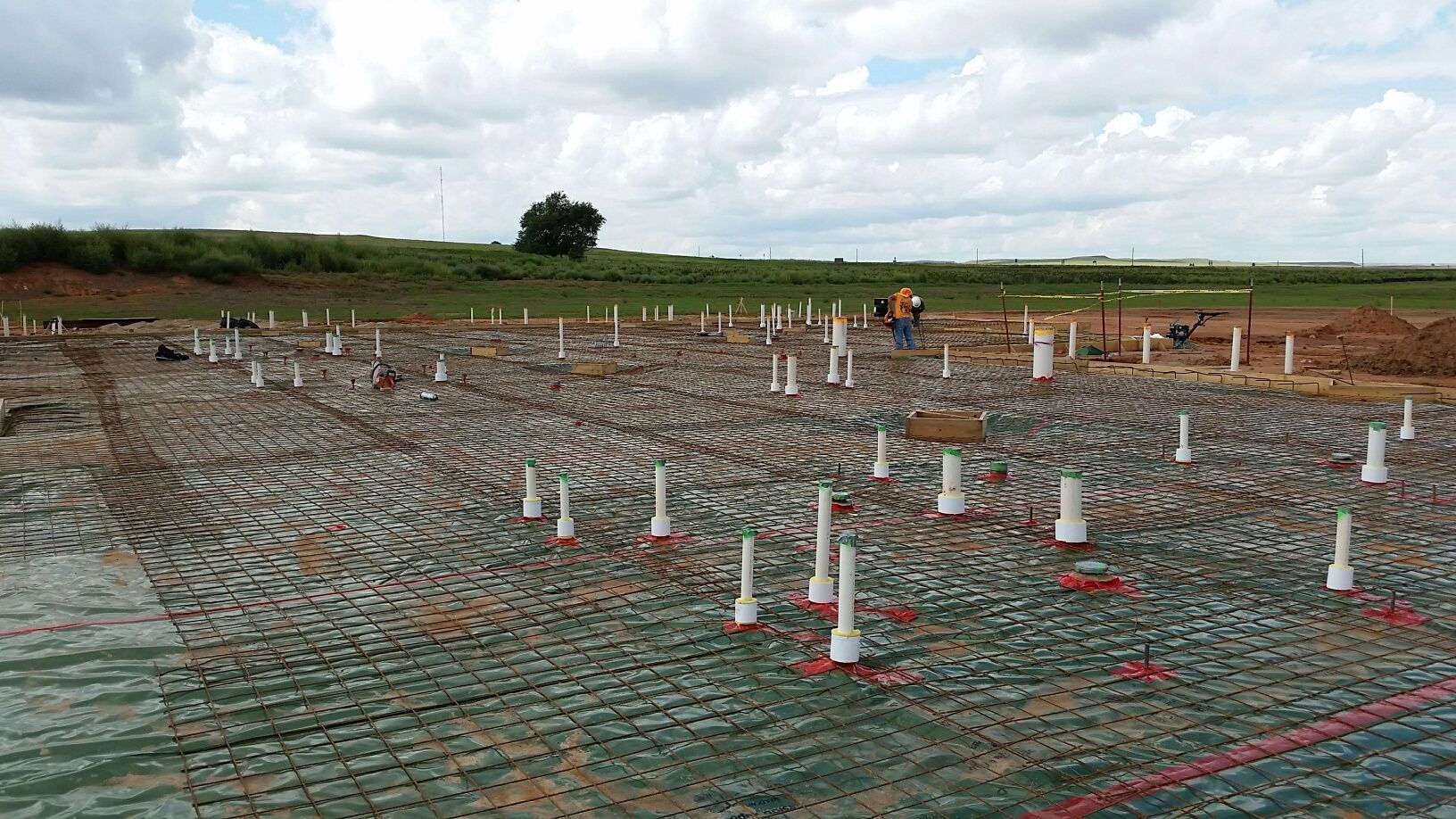 A construction site with a lot of pipes and cones on the ground.