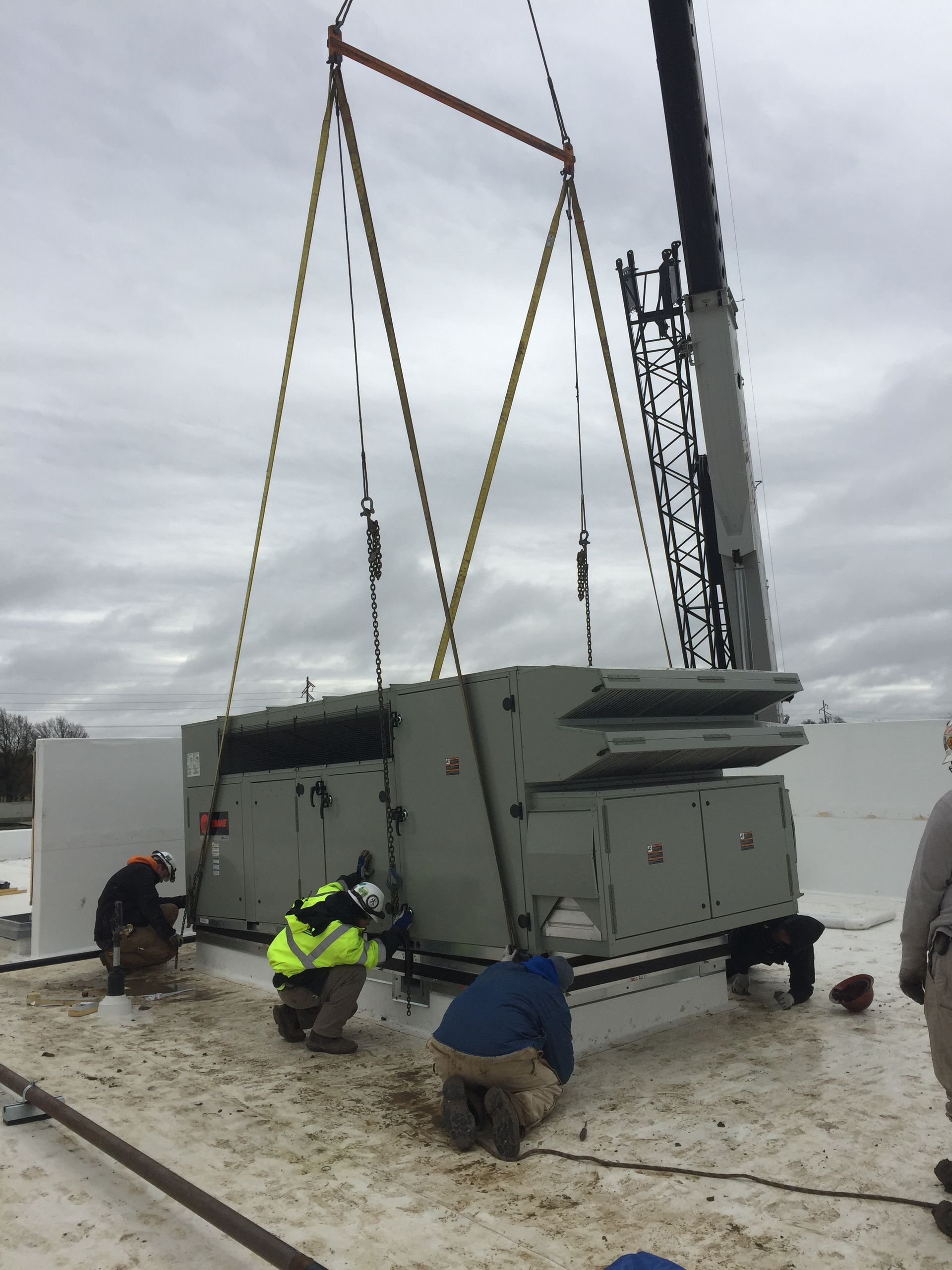 A large piece of equipment is being lifted by a crane