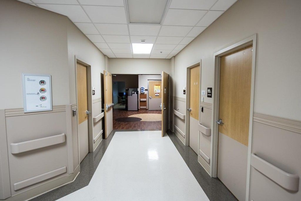 A hospital hallway with a lot of doors and a sign on the wall.