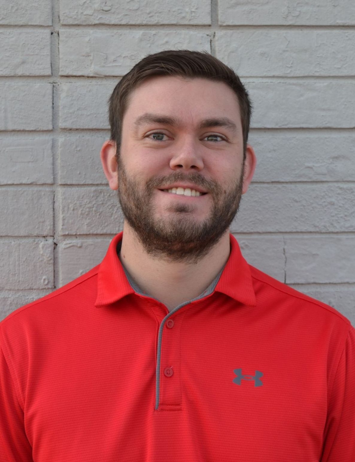 A man named Colton Berblinger with a beard wearing a red under armour polo shirt