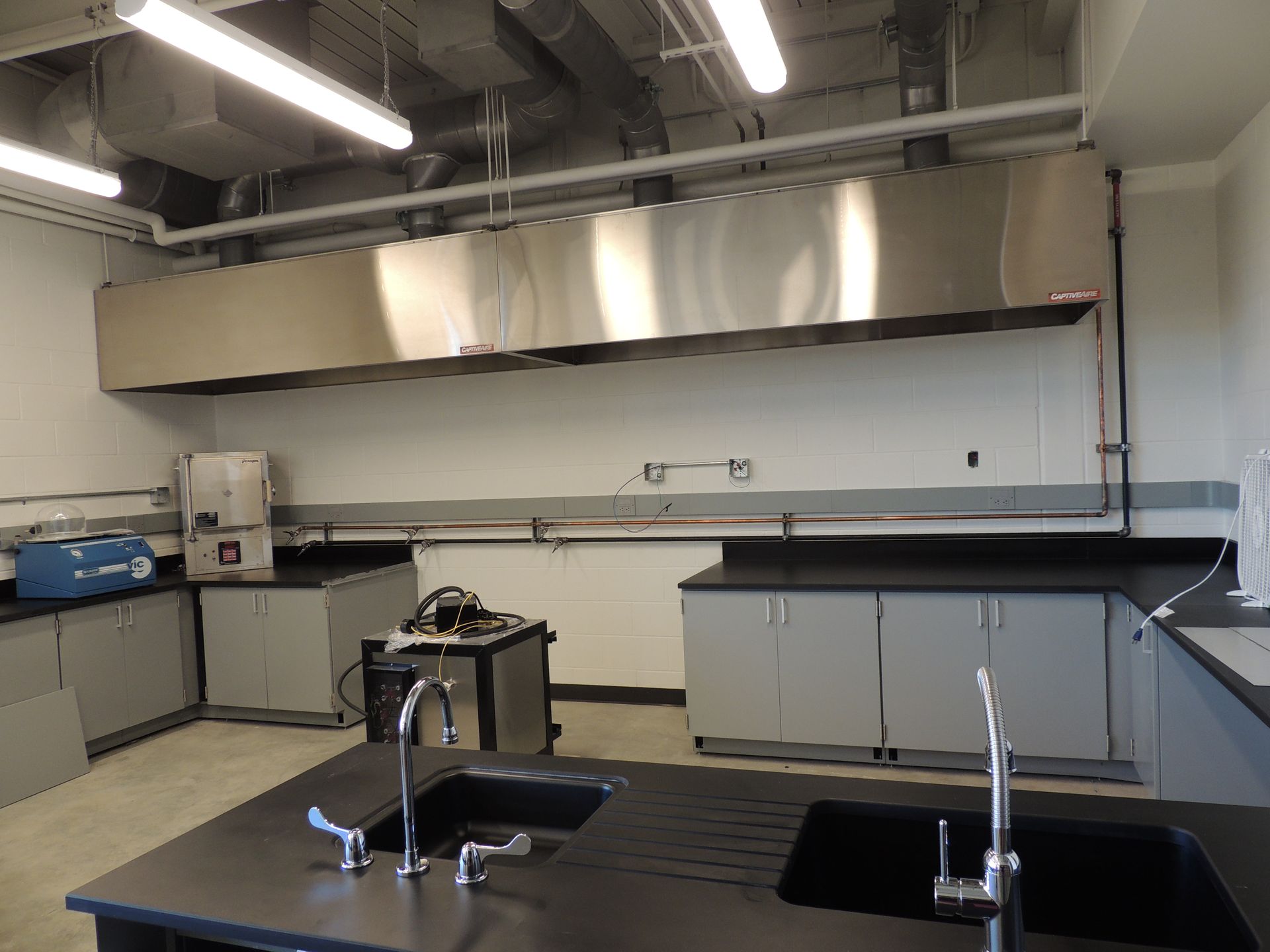 A kitchen with two sinks and a stainless steel hood