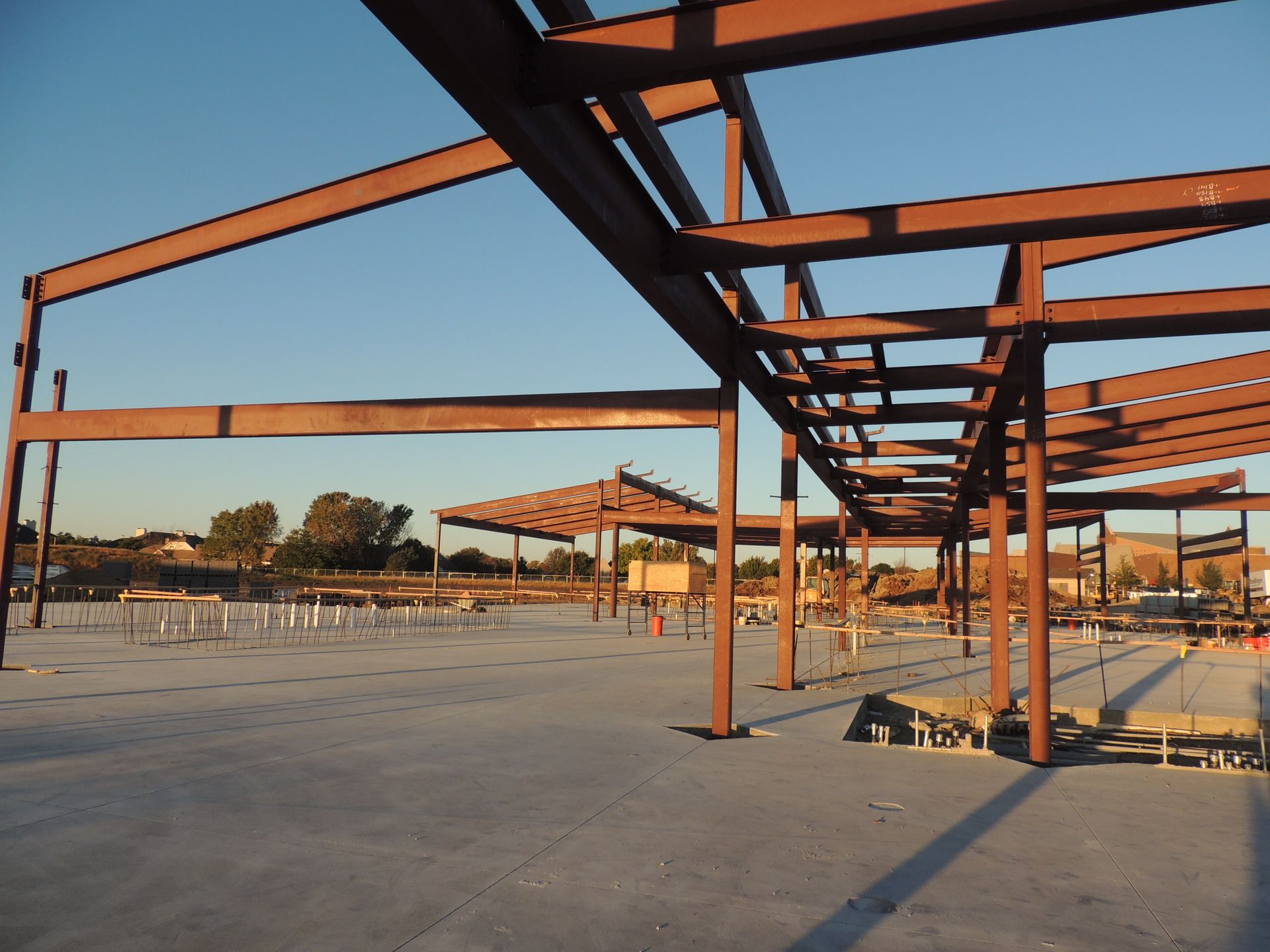 A large metal structure is under construction with a blue sky in the background