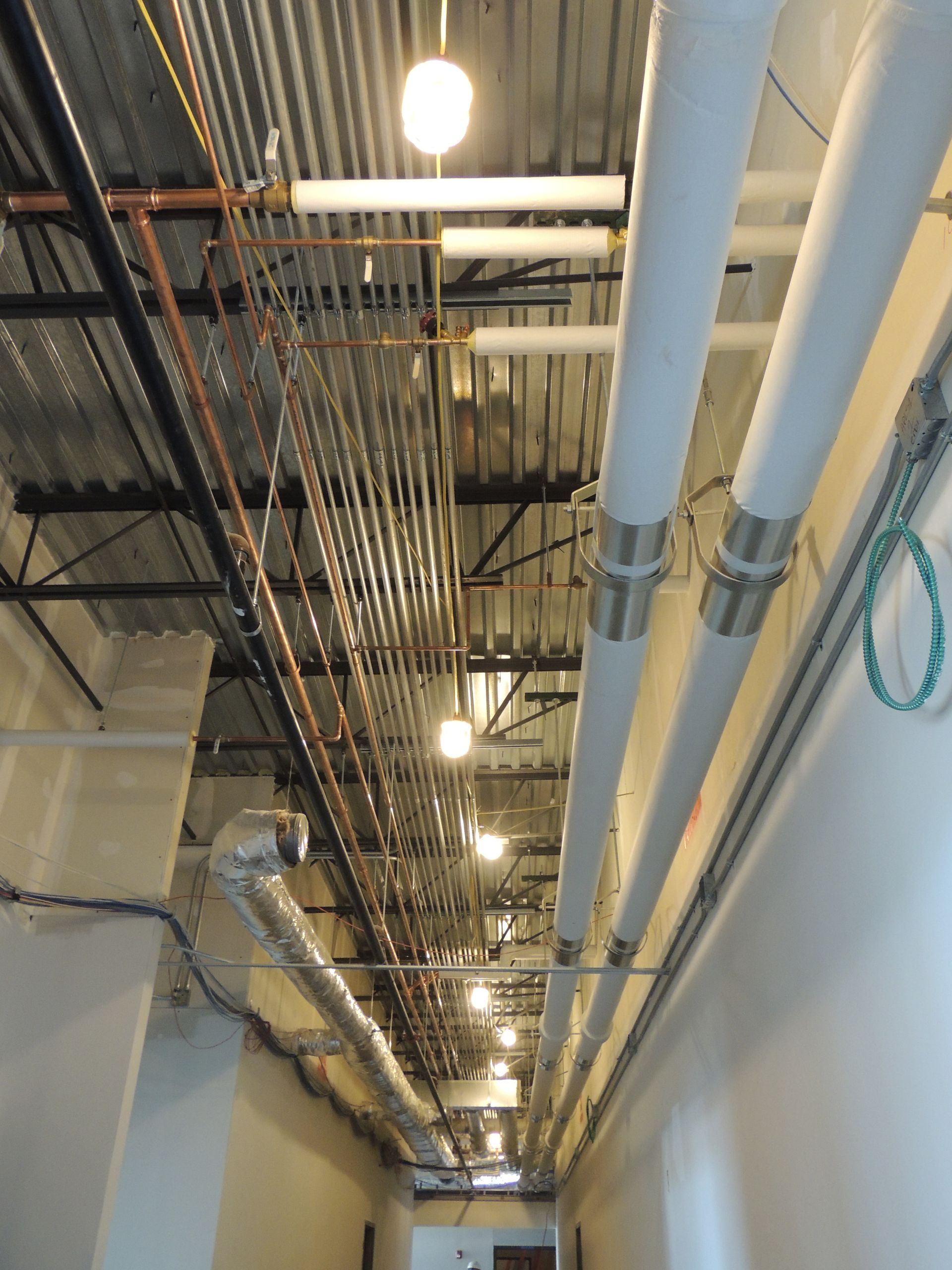 A hallway with a lot of pipes hanging from the ceiling