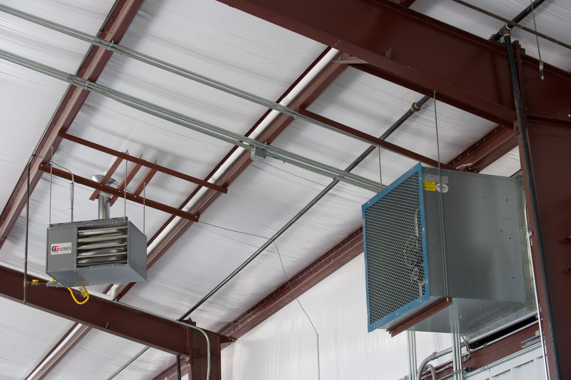 Two heaters are hanging from the ceiling of a building