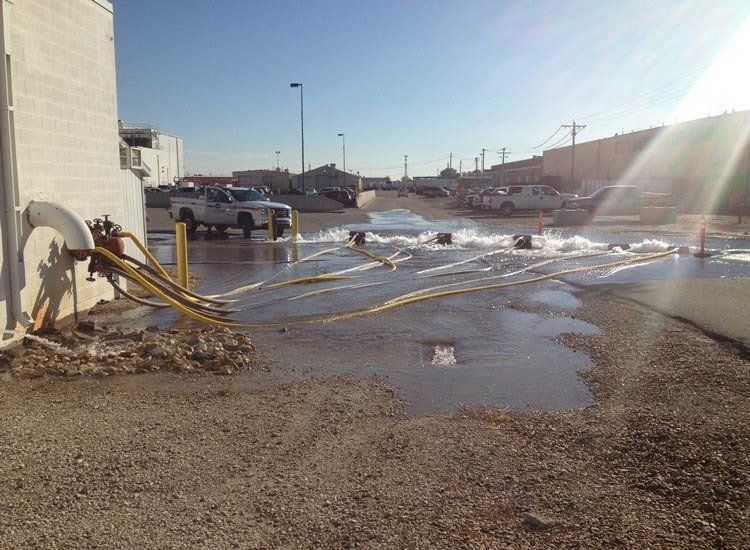 A white truck is parked in a parking lot next to a puddle of water.