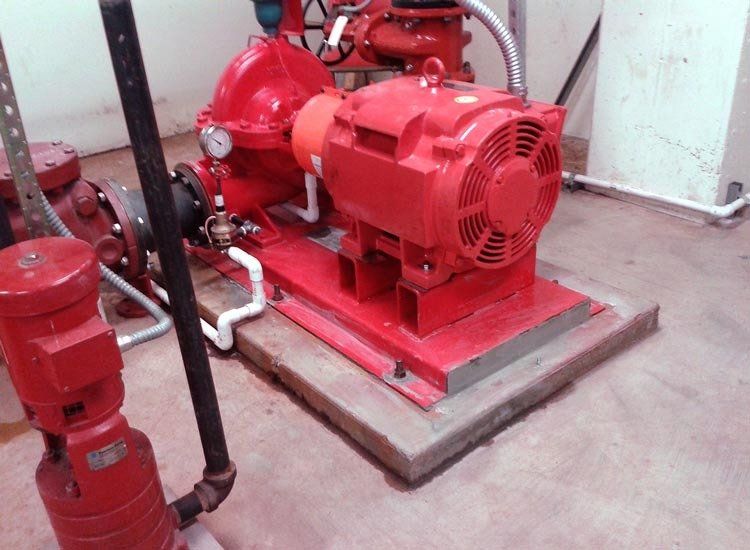 A red pump is sitting on a concrete platform in a room.