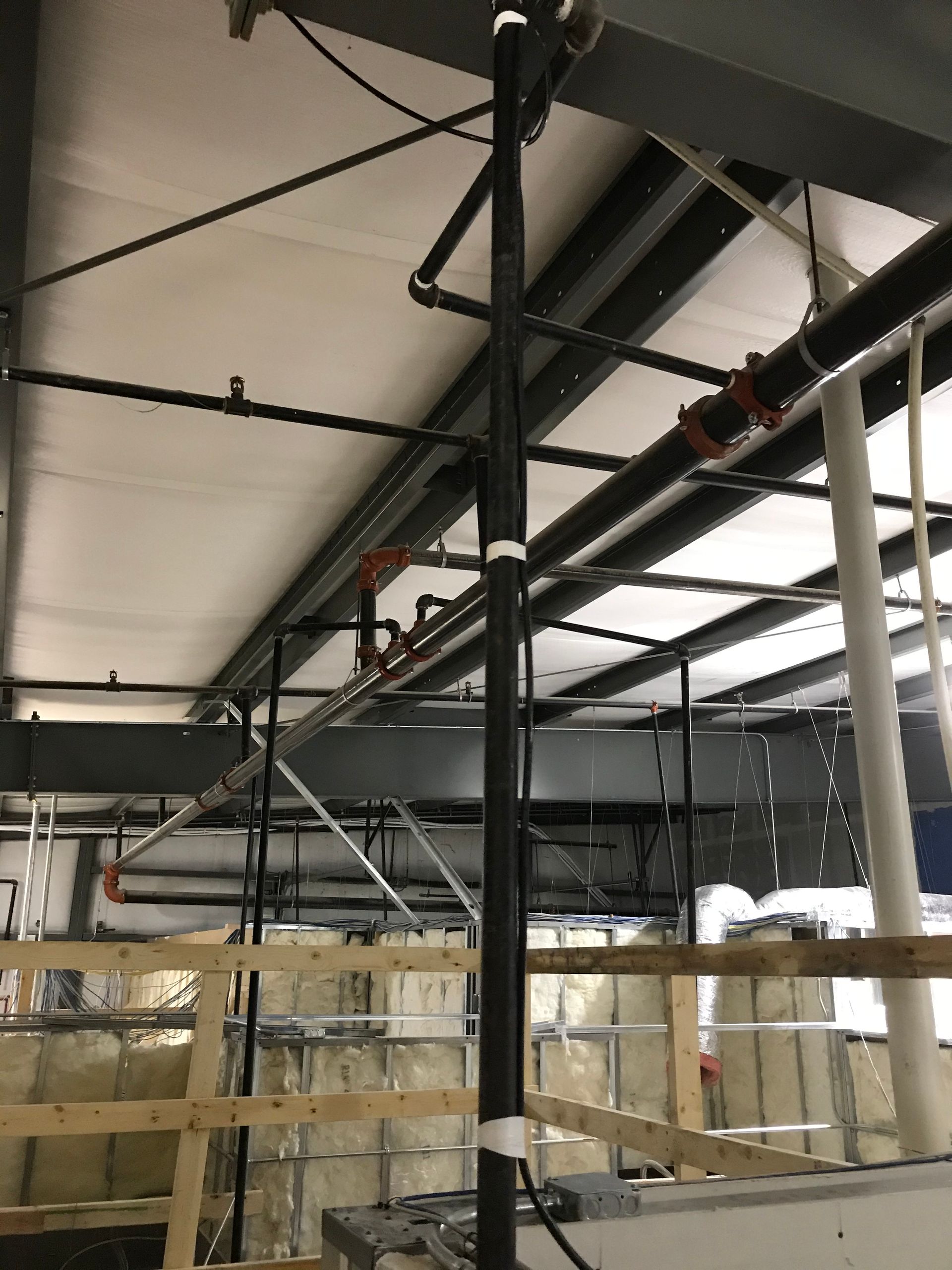 A building under construction with pipes hanging from the ceiling