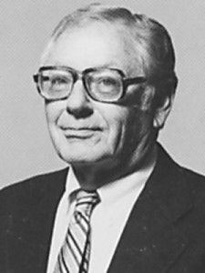 A black and white photo of a man wearing glasses and a suit and tie.