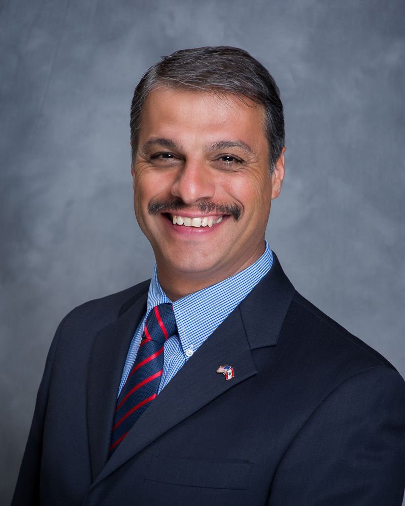 A man Joe Samia in a suit and tie is smiling for the camera.