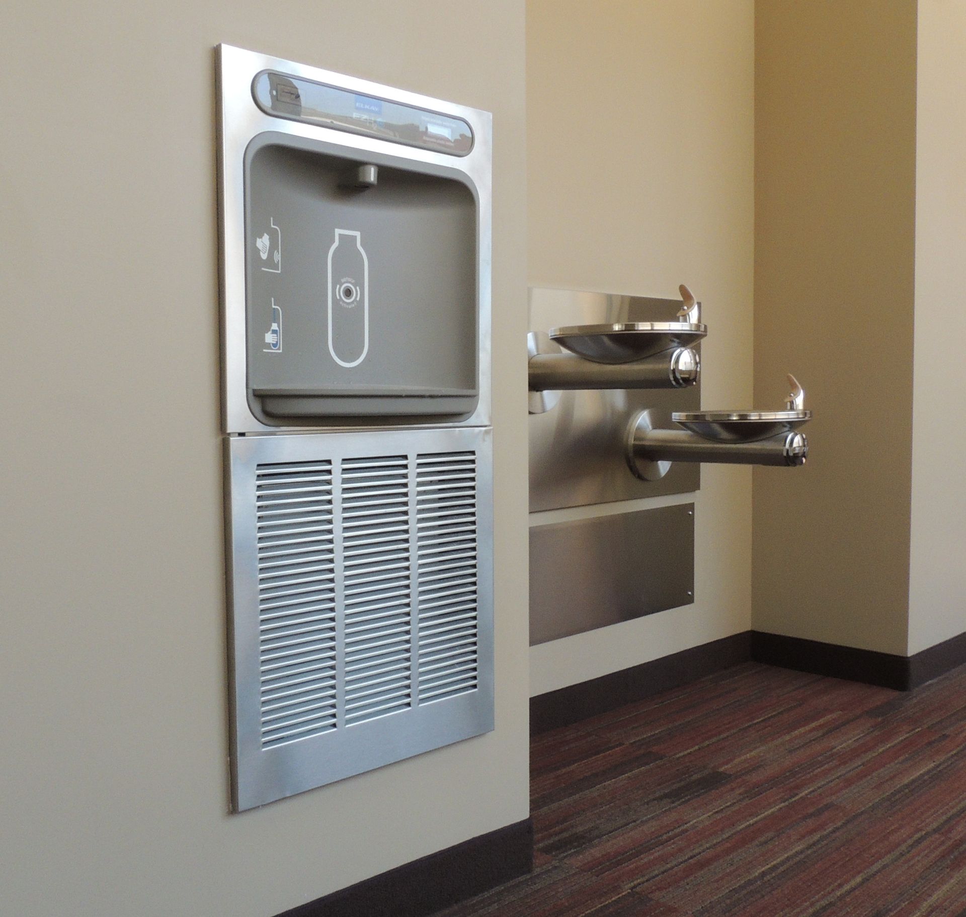 A wall mounted water fountain with a bottle icon on it
