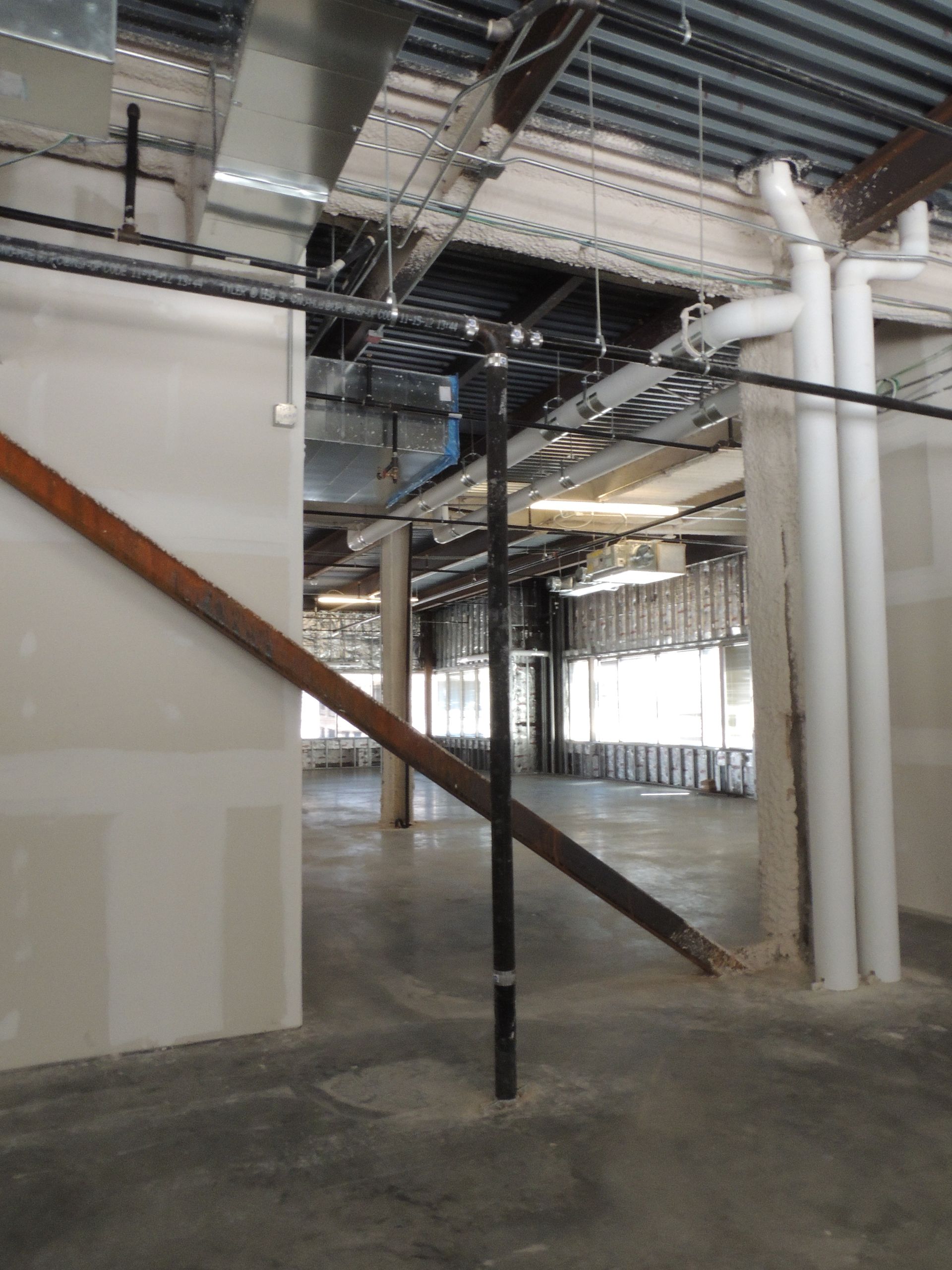 A large empty room with pipes and stairs