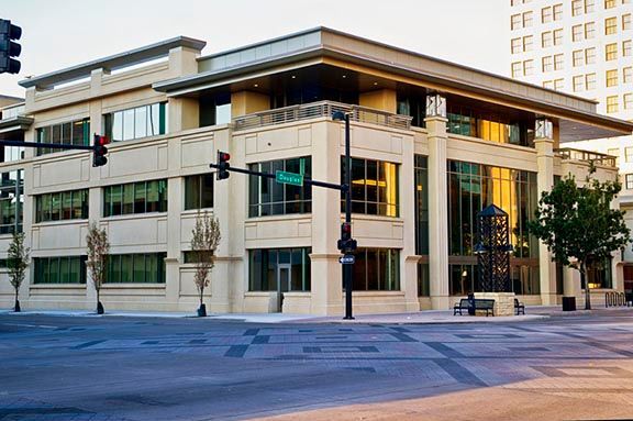 A large building with a lot of windows is sitting on the corner of a city street.