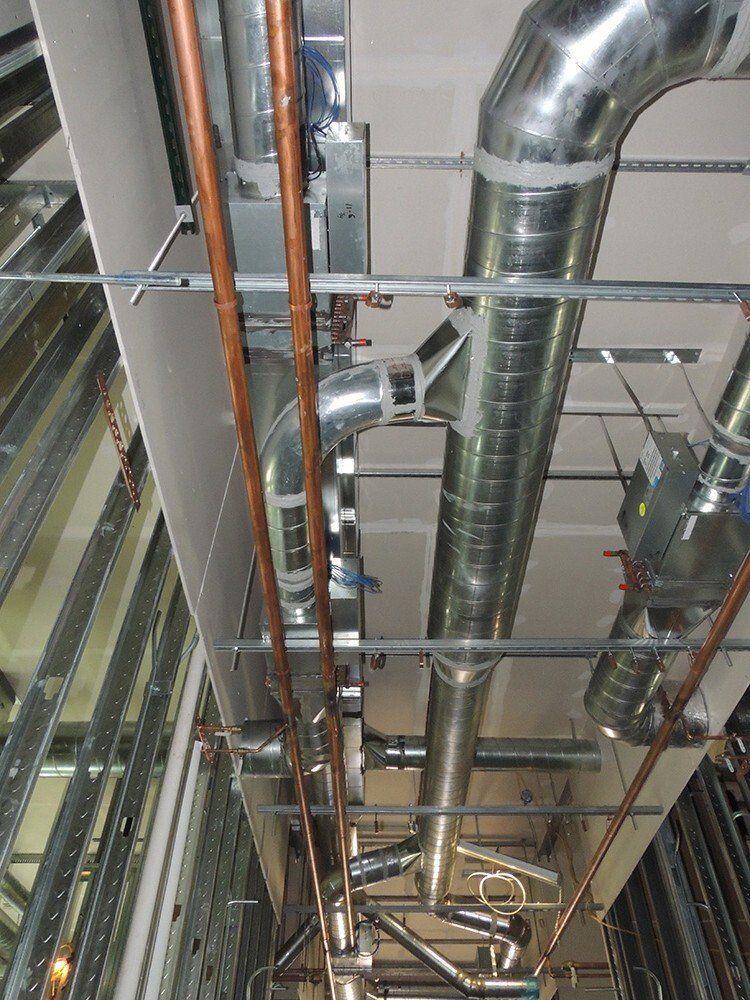 A bunch of pipes are hanging from the ceiling of a building