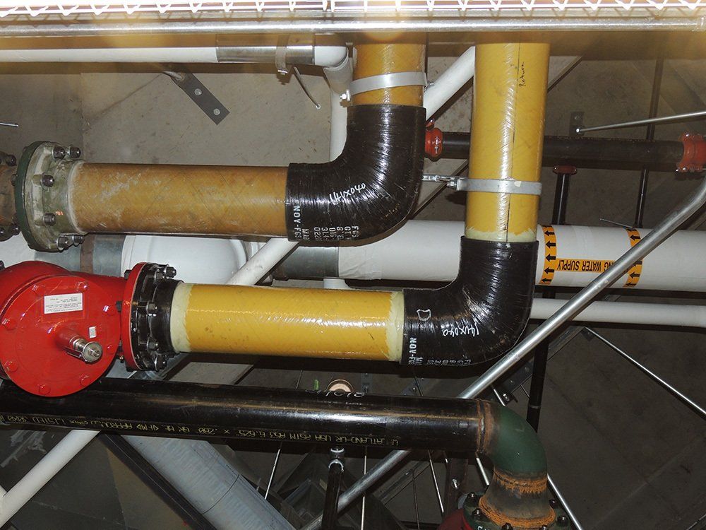 A bunch of pipes are connected to each other and one of them has a red valve on it