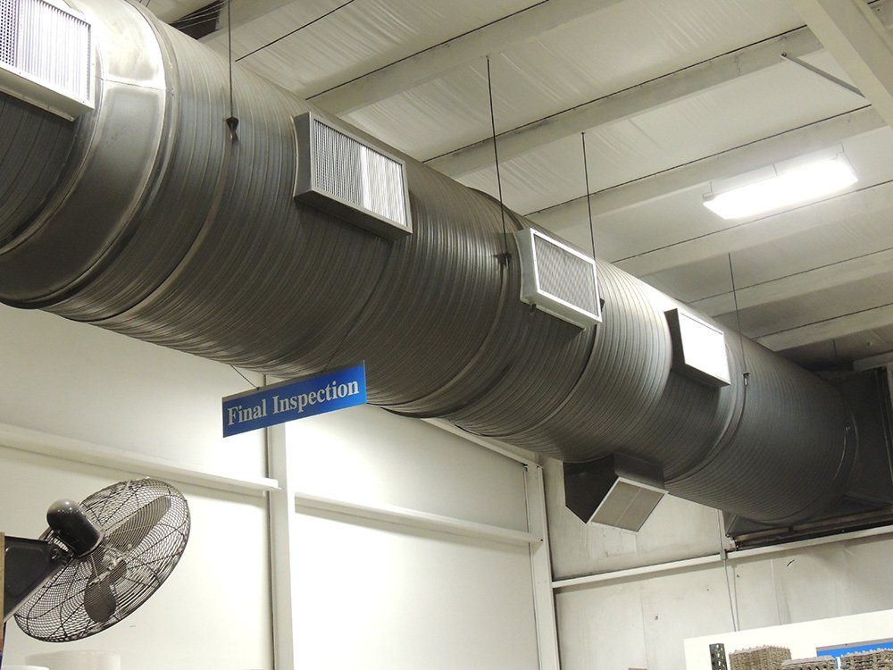 A blue sign hangs from the ceiling of a building next to a fan.