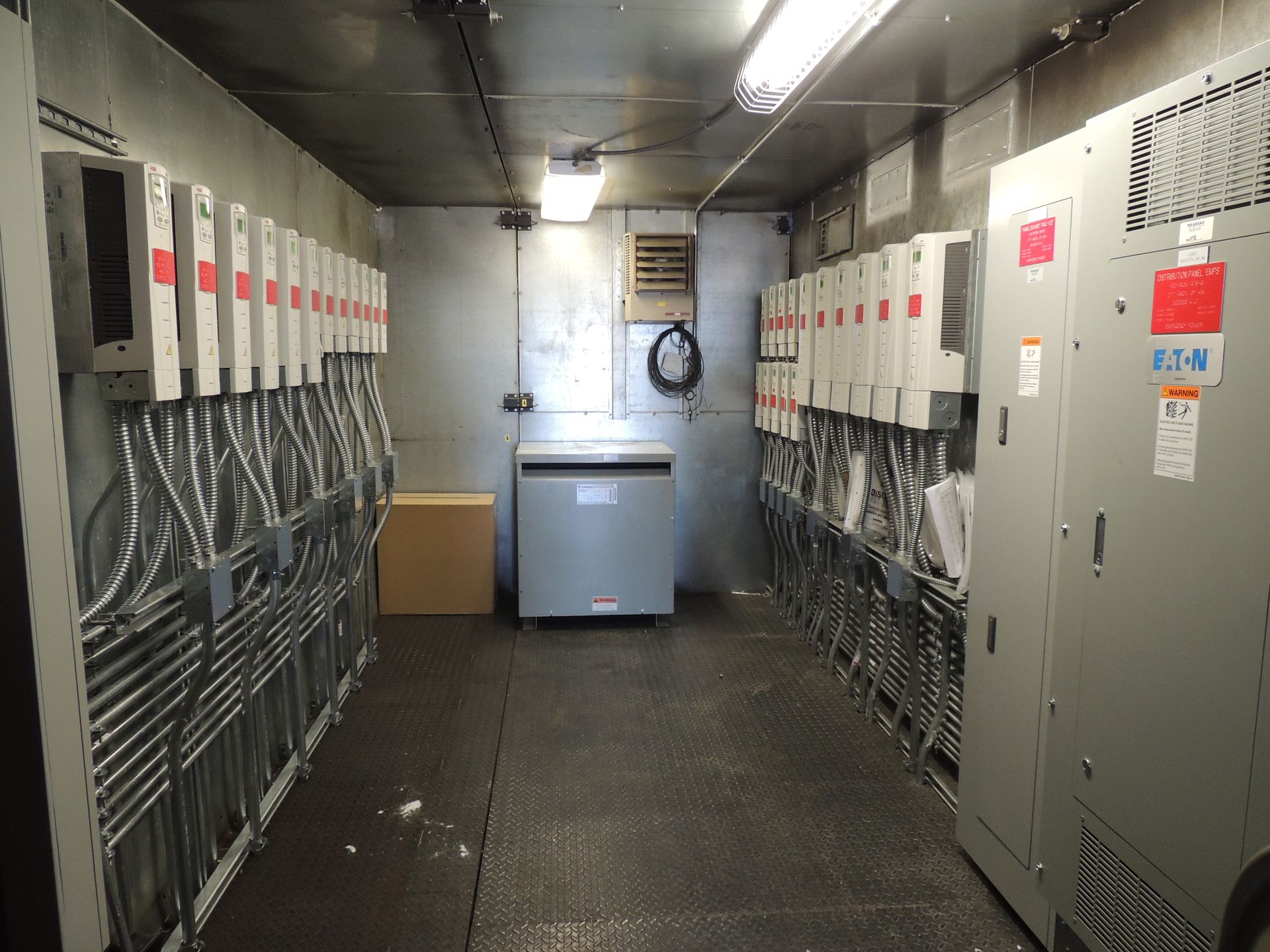 A room with a lot of electrical boxes and a refrigerator