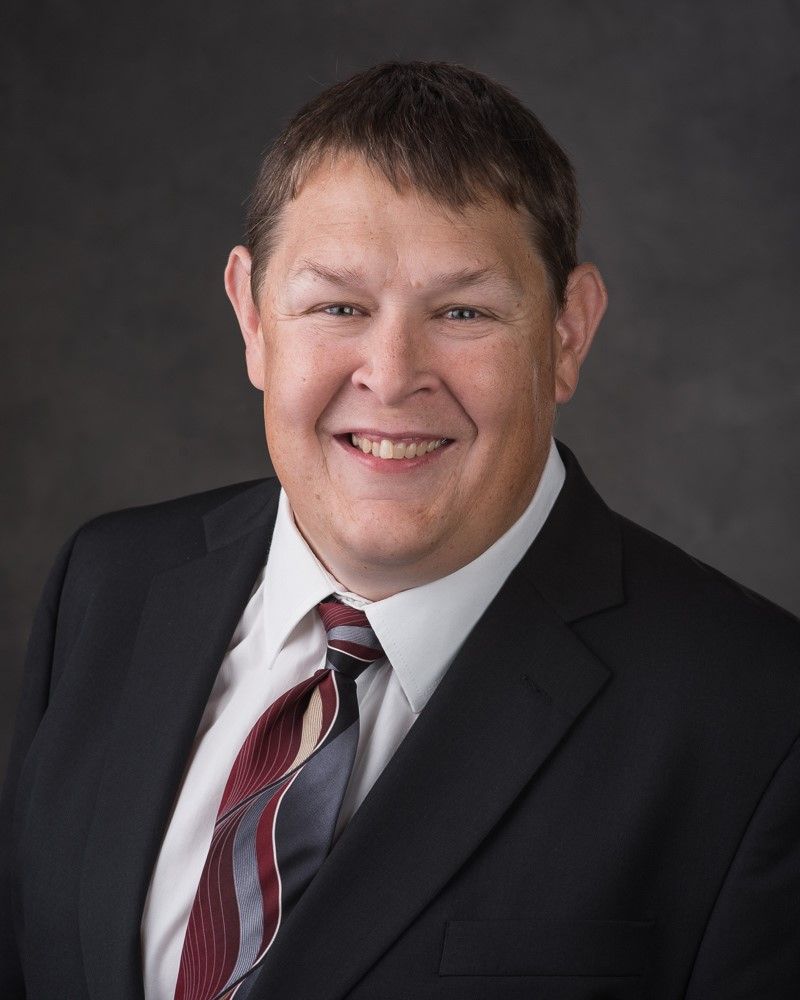 A man in a suit and tie is smiling for the camera