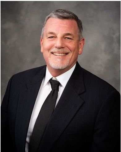 A man in a suit and tie is smiling for the camera