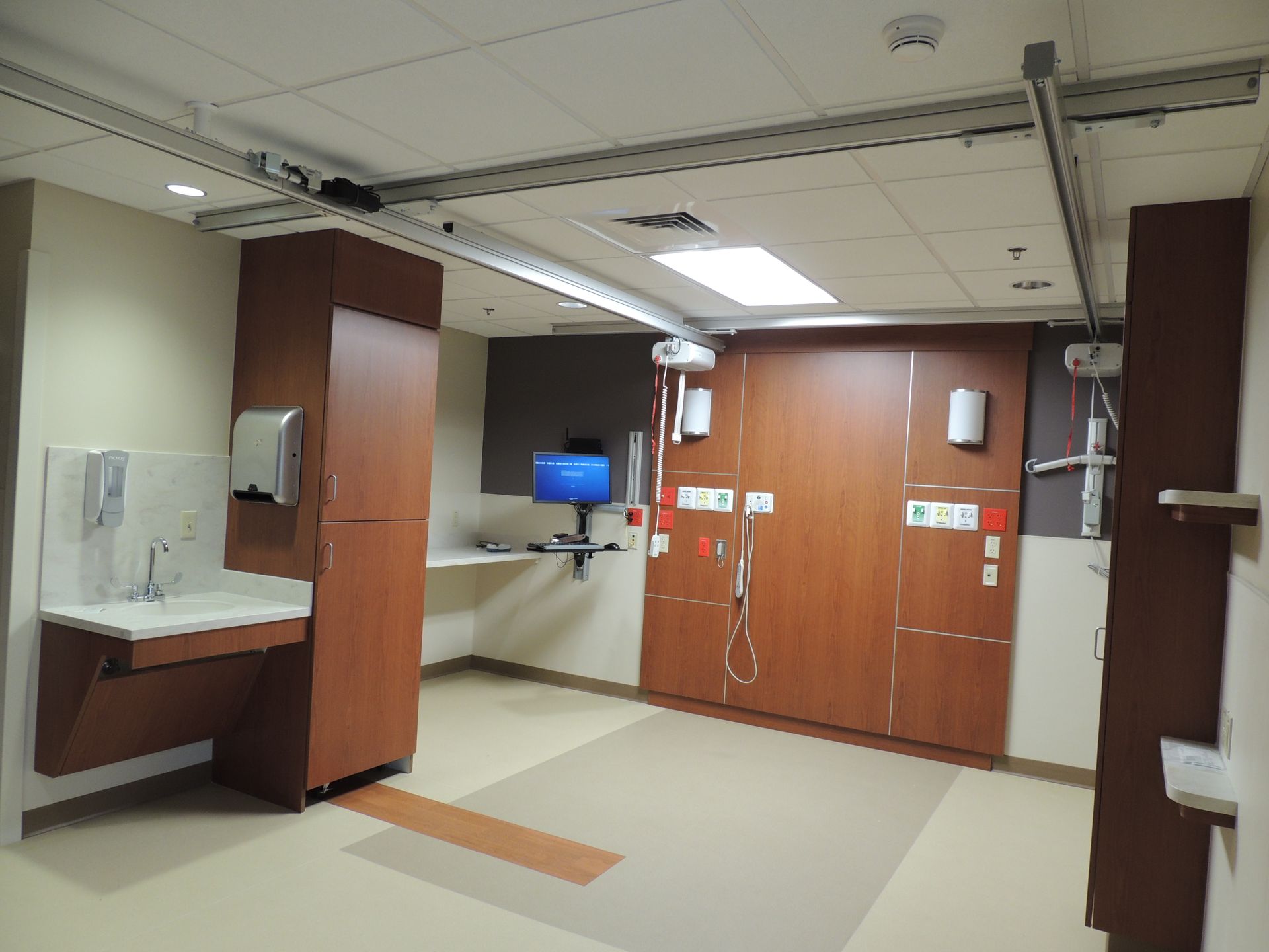 An empty room in a hospital with a computer on the wall.