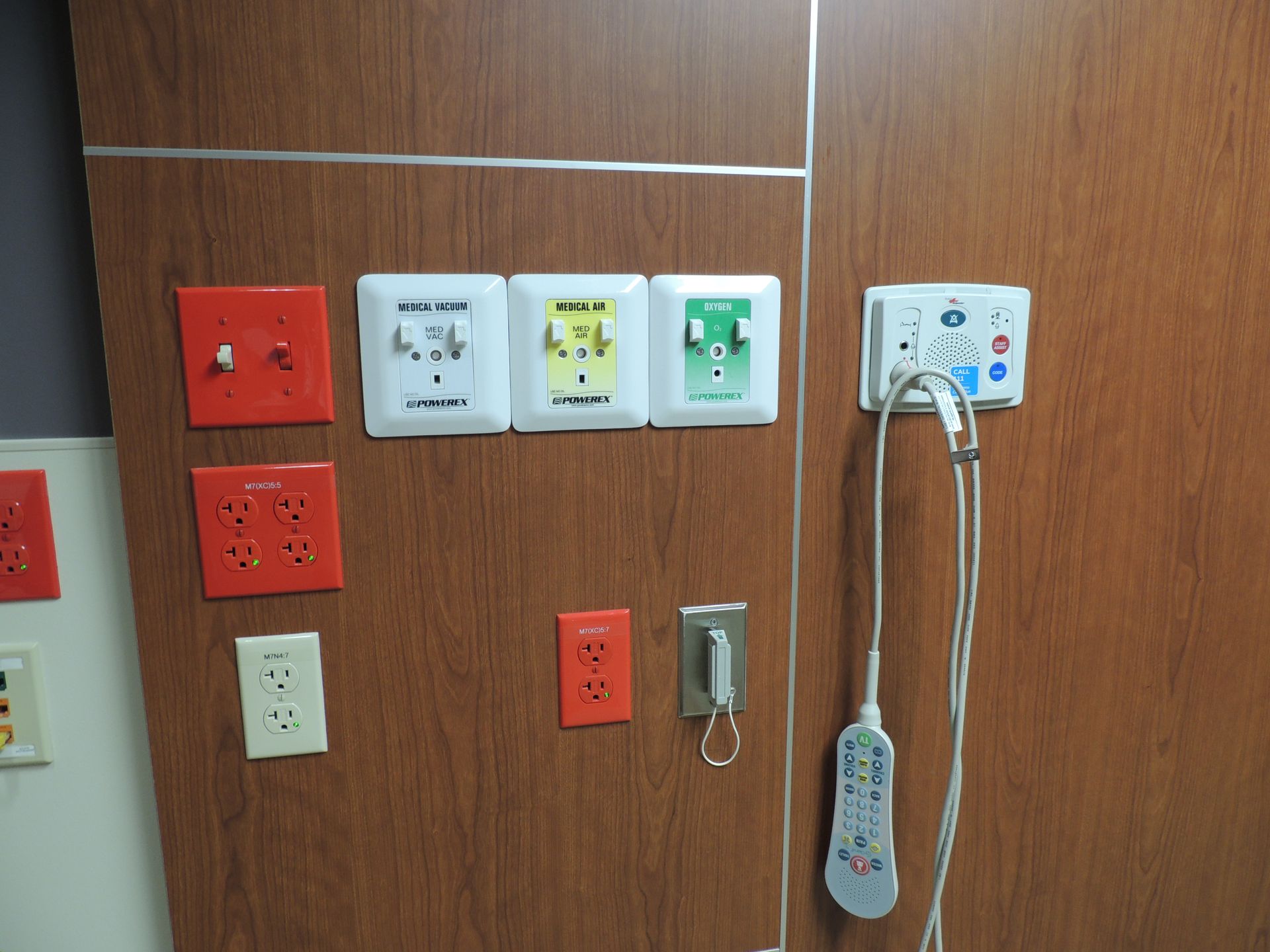 A wall with a bunch of electrical outlets and a remote control