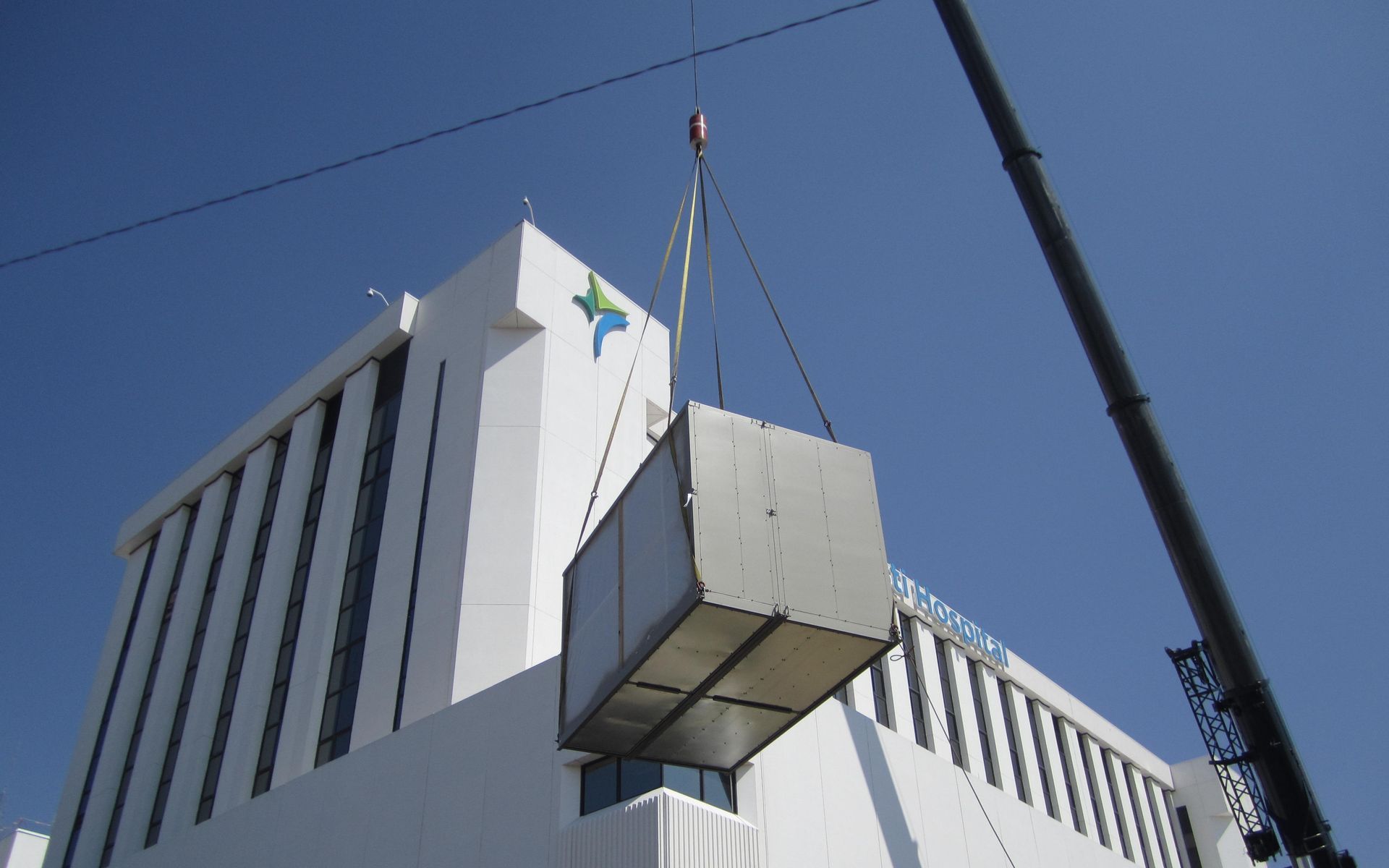 A large white building is being lifted by a crane