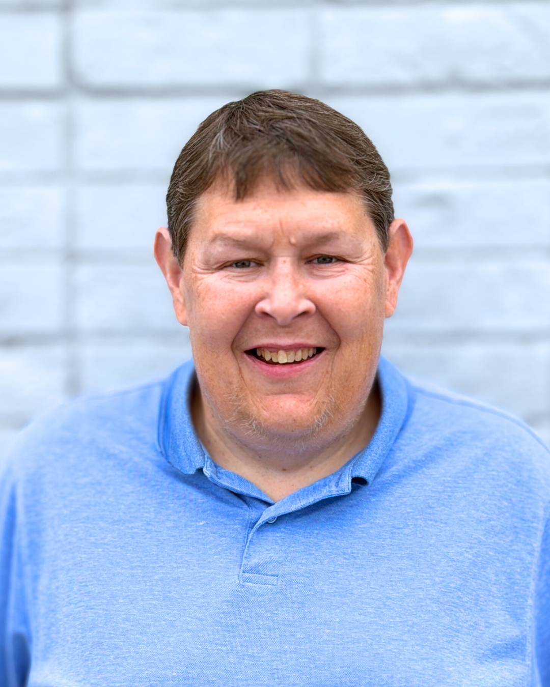 A man in a blue polo is smiling for the camera
