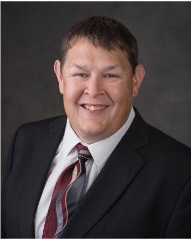 A man in a suit and tie is smiling for the camera