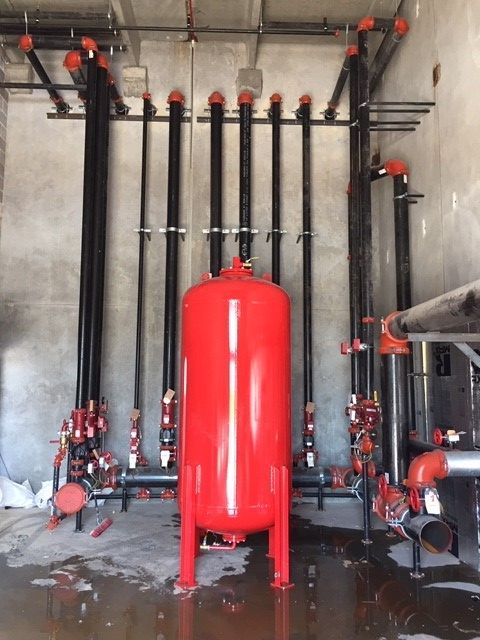 A large red tank in a room with pipes