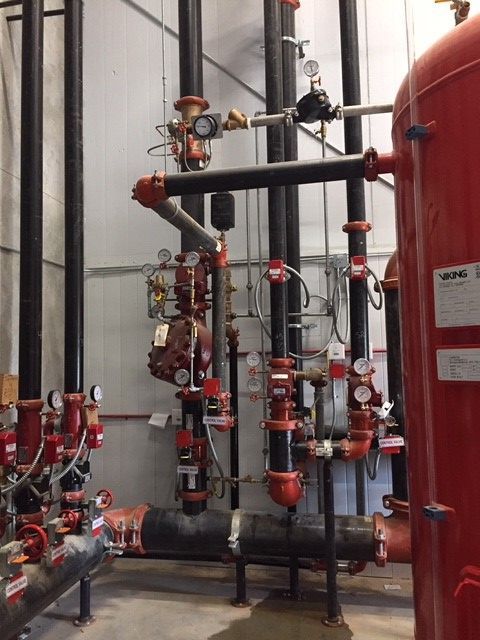 A room with a lot of pipes and a red tank that says vpc on it