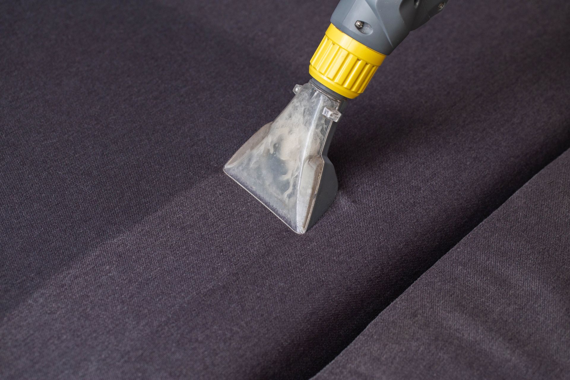 Steam cleaner nozzle cleaning dark fabric.