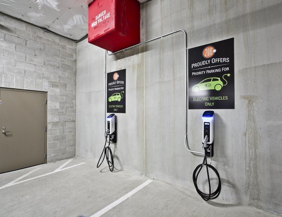 Two electric car charging stations are hanging on a wall in a parking garage.