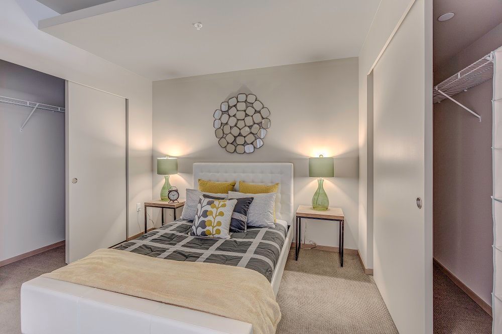 A bedroom with a bed , nightstands , lamps and a walk in closet.