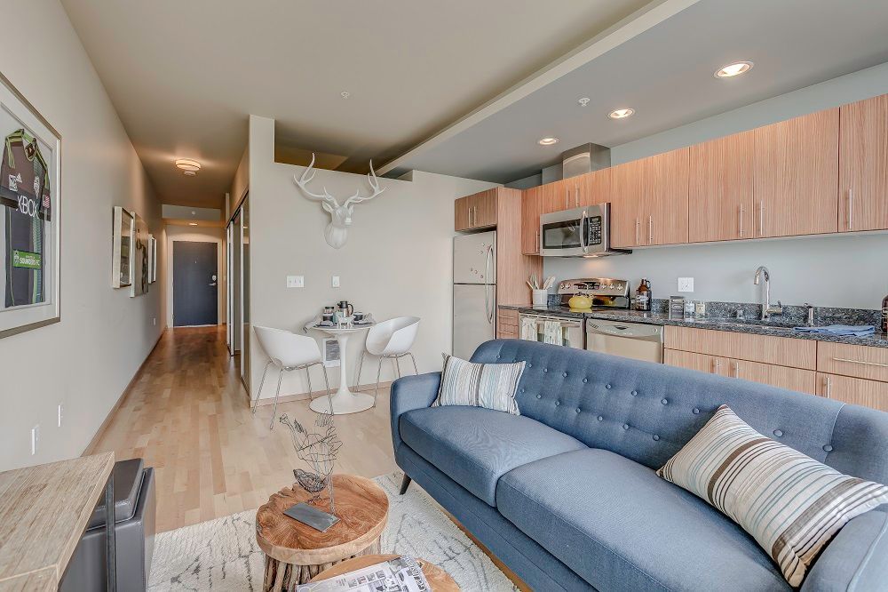 A living room with a couch , table , chairs and a kitchen.