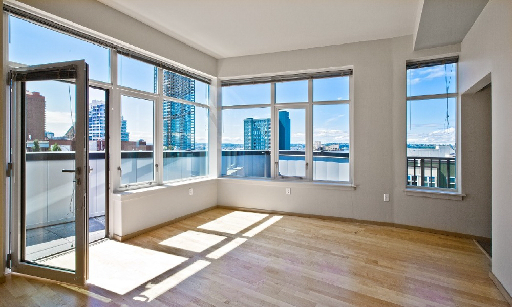 An empty living room with lots of windows and a balcony