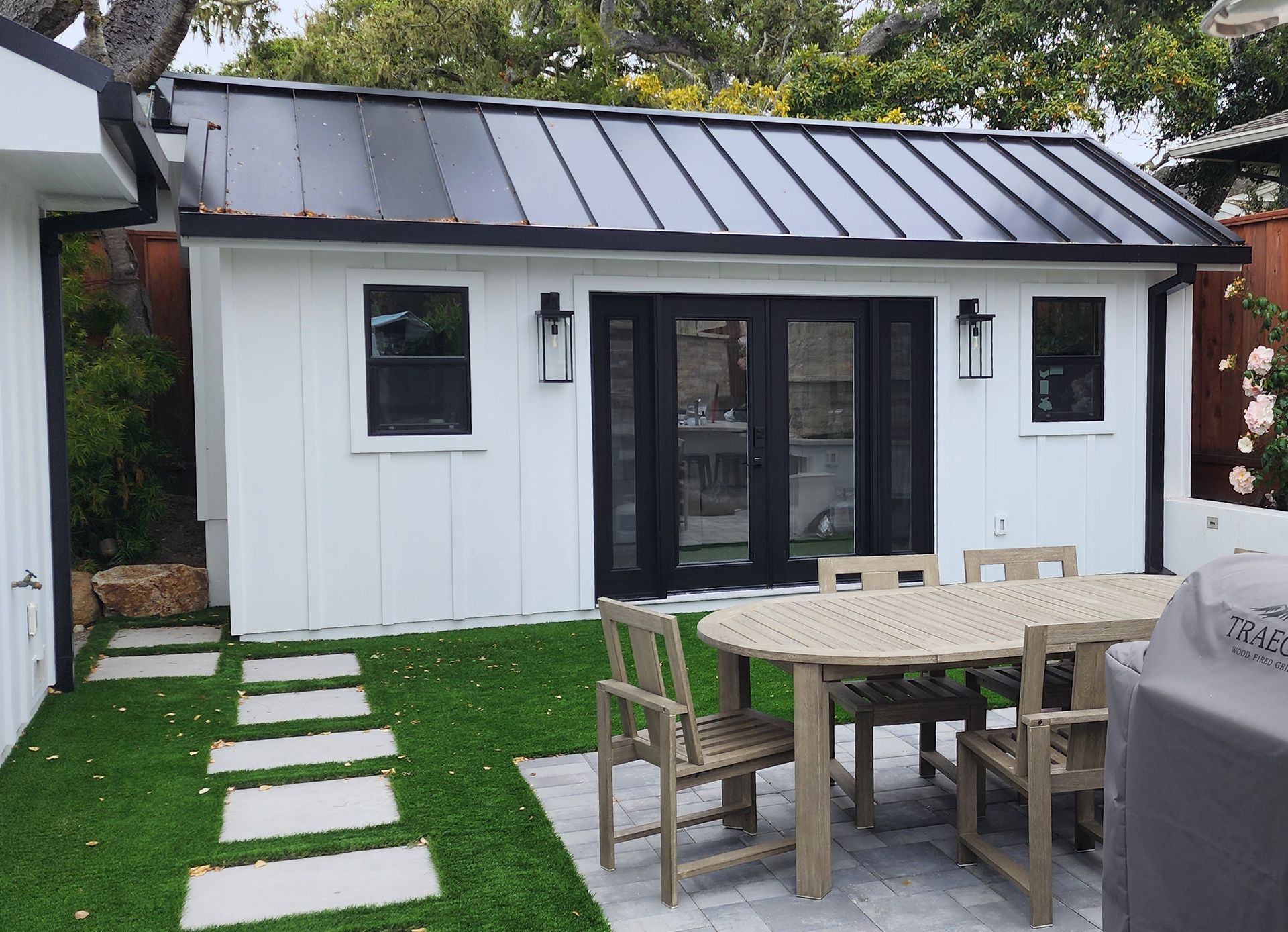 A white house with a black roof and a table and chairs in front of it