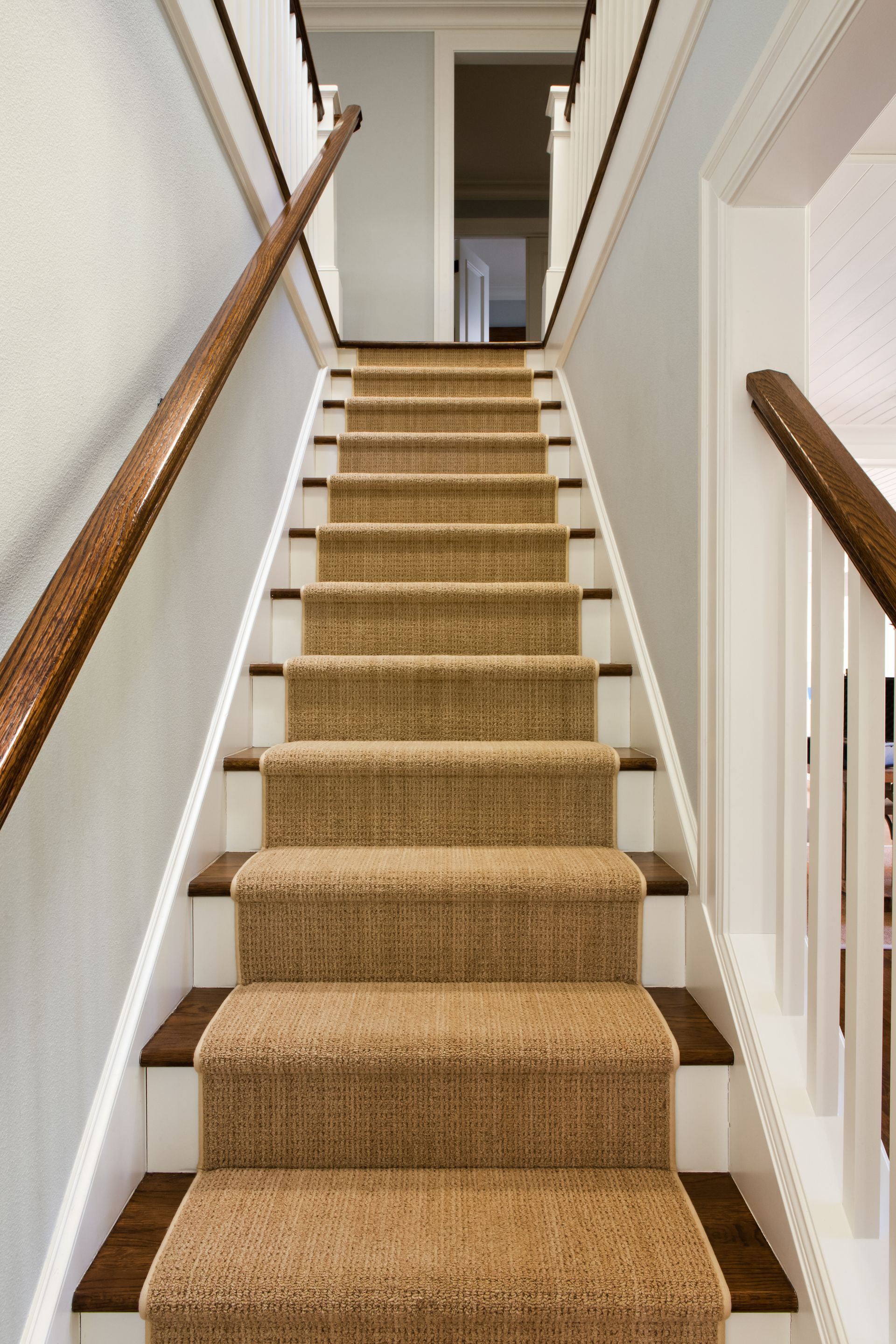 A set of stairs with a brown carpet and a wooden railing