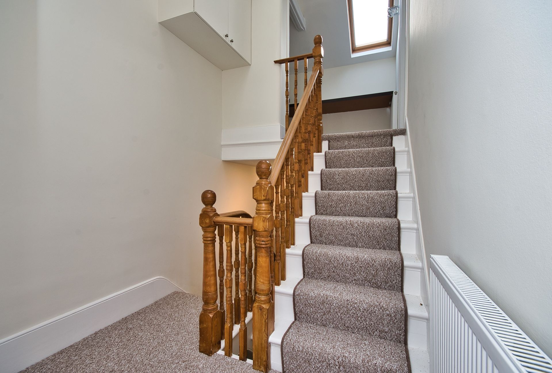 A staircase with carpeted steps and a wooden railing