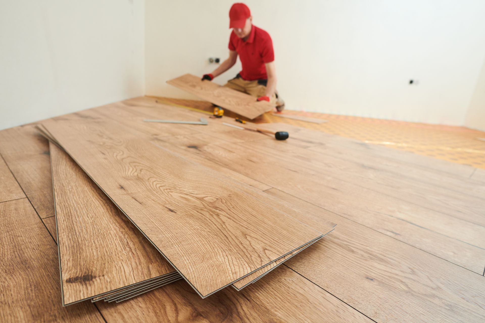 A man is installing a wooden floor in a room.