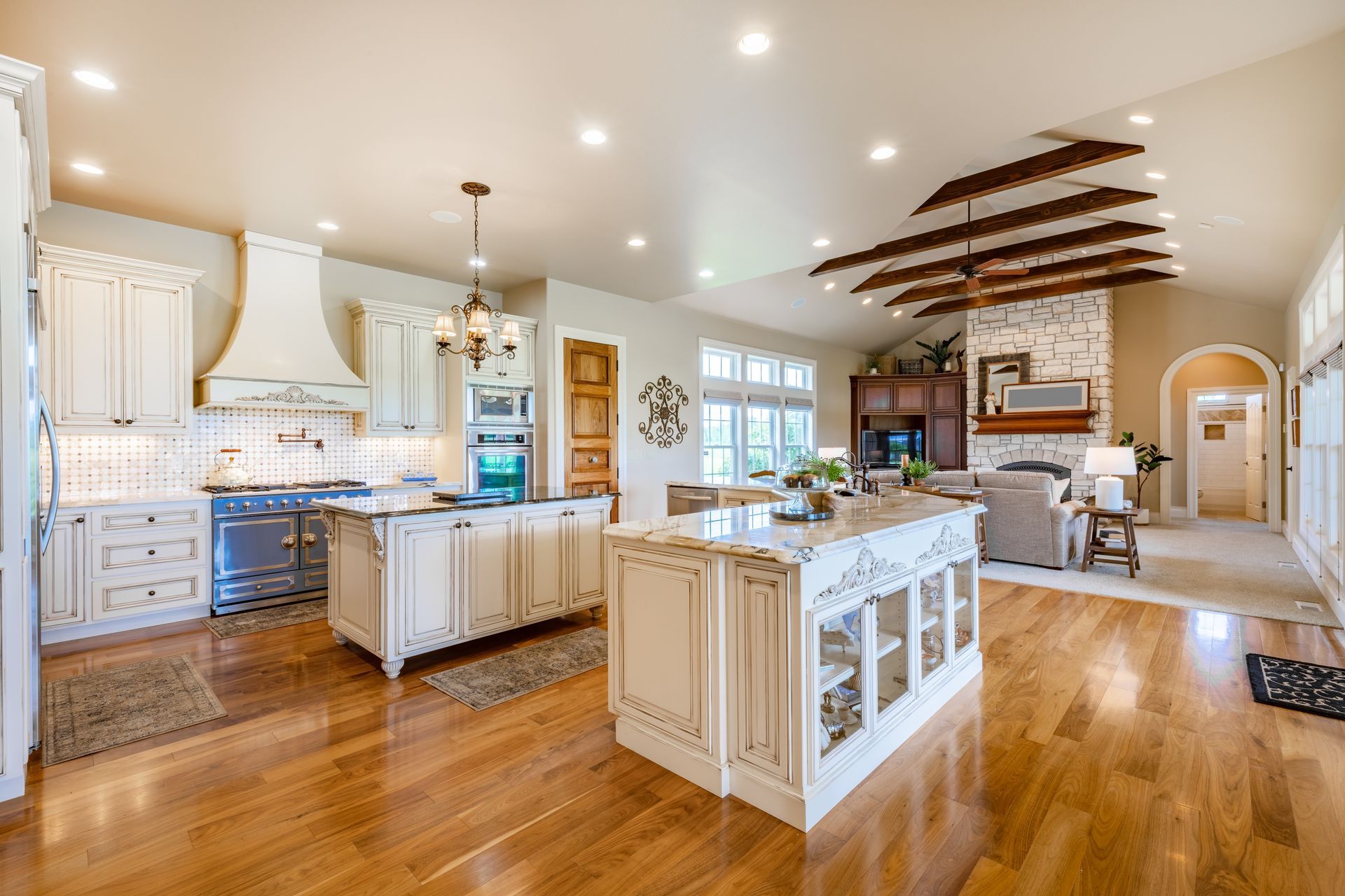 A large kitchen with white cabinets and hardwood floors and a large island in the middle.