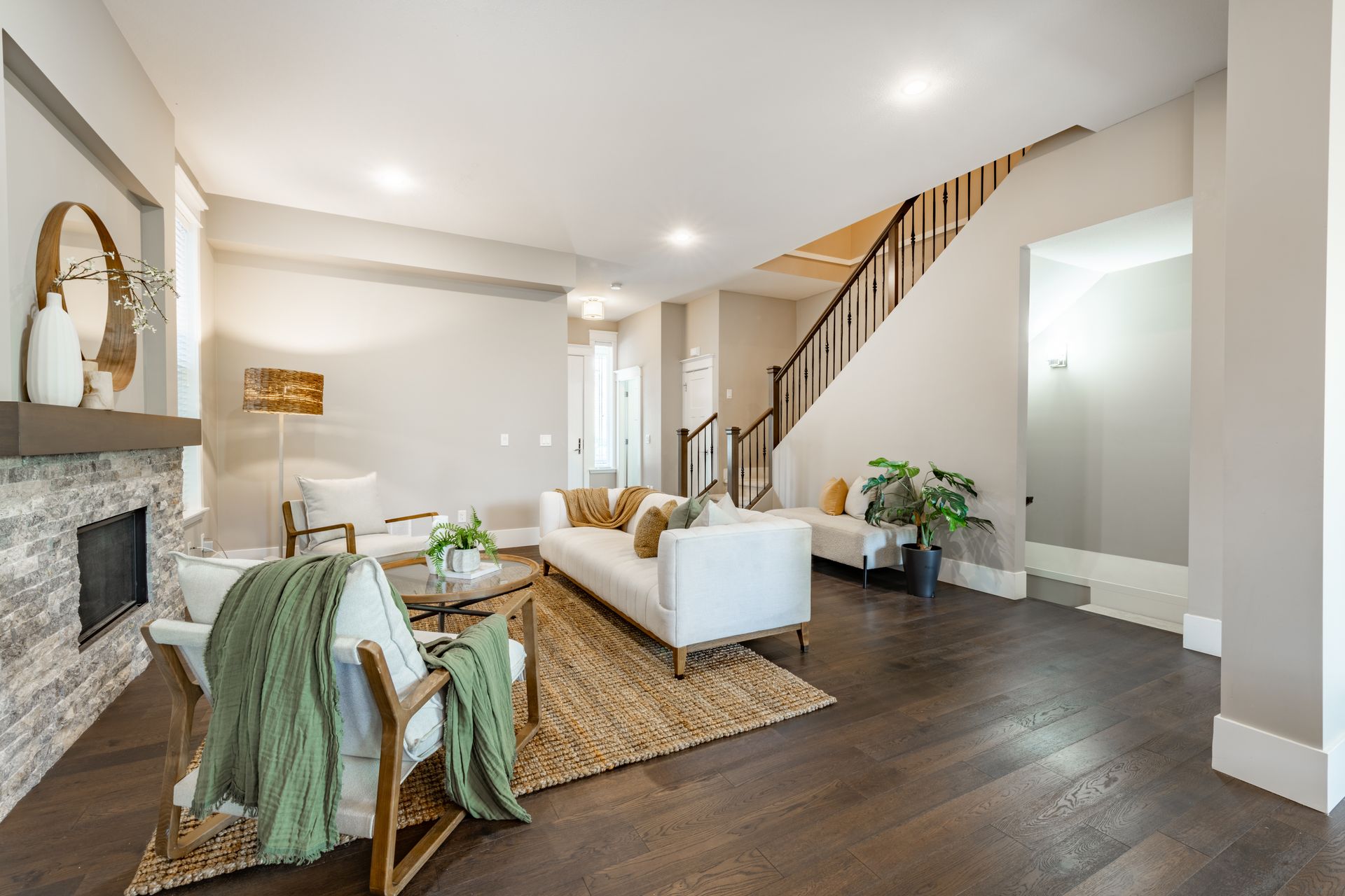 A living room with a couch , chairs , fireplace and stairs.