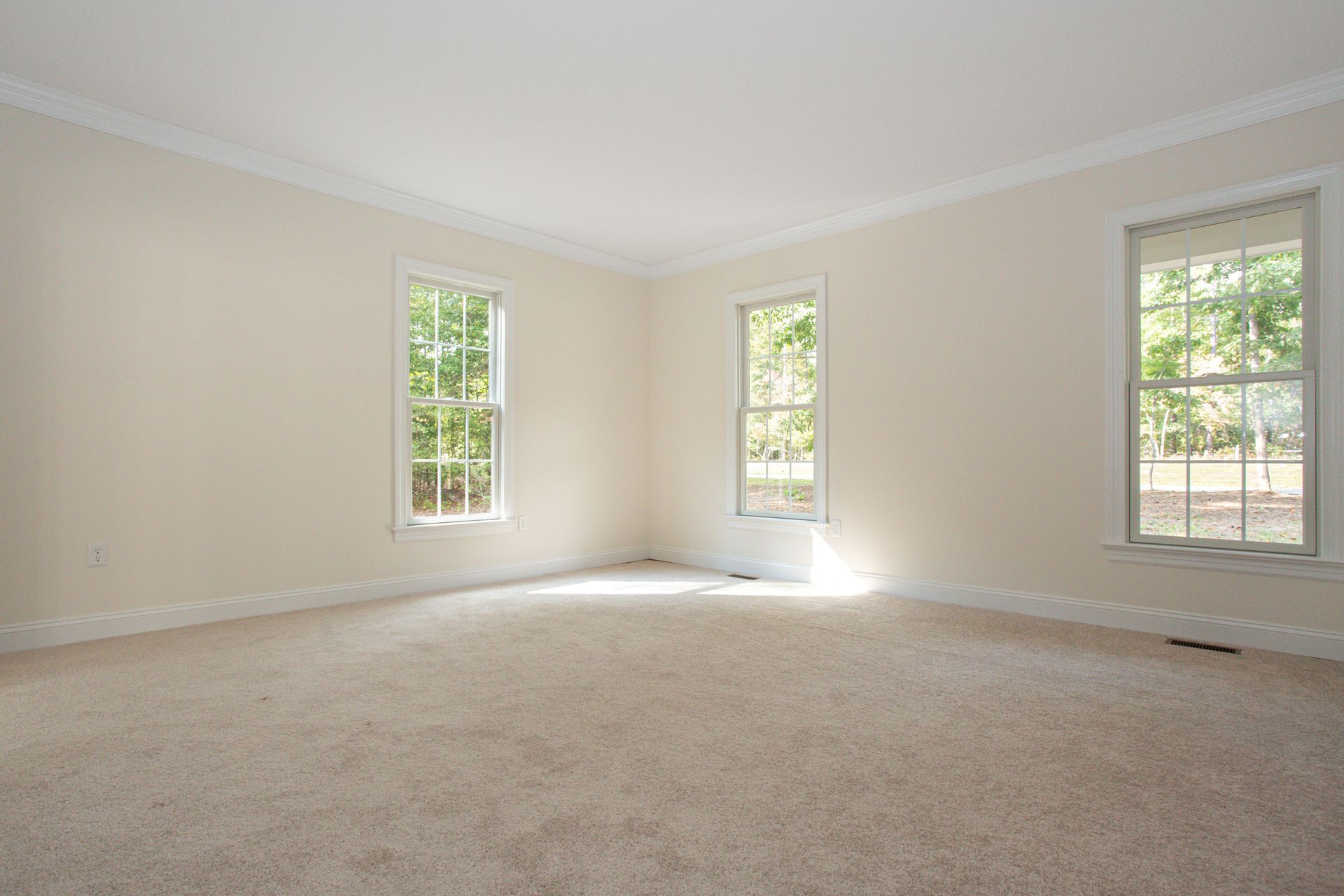 An empty room with two windows and a carpeted floor.