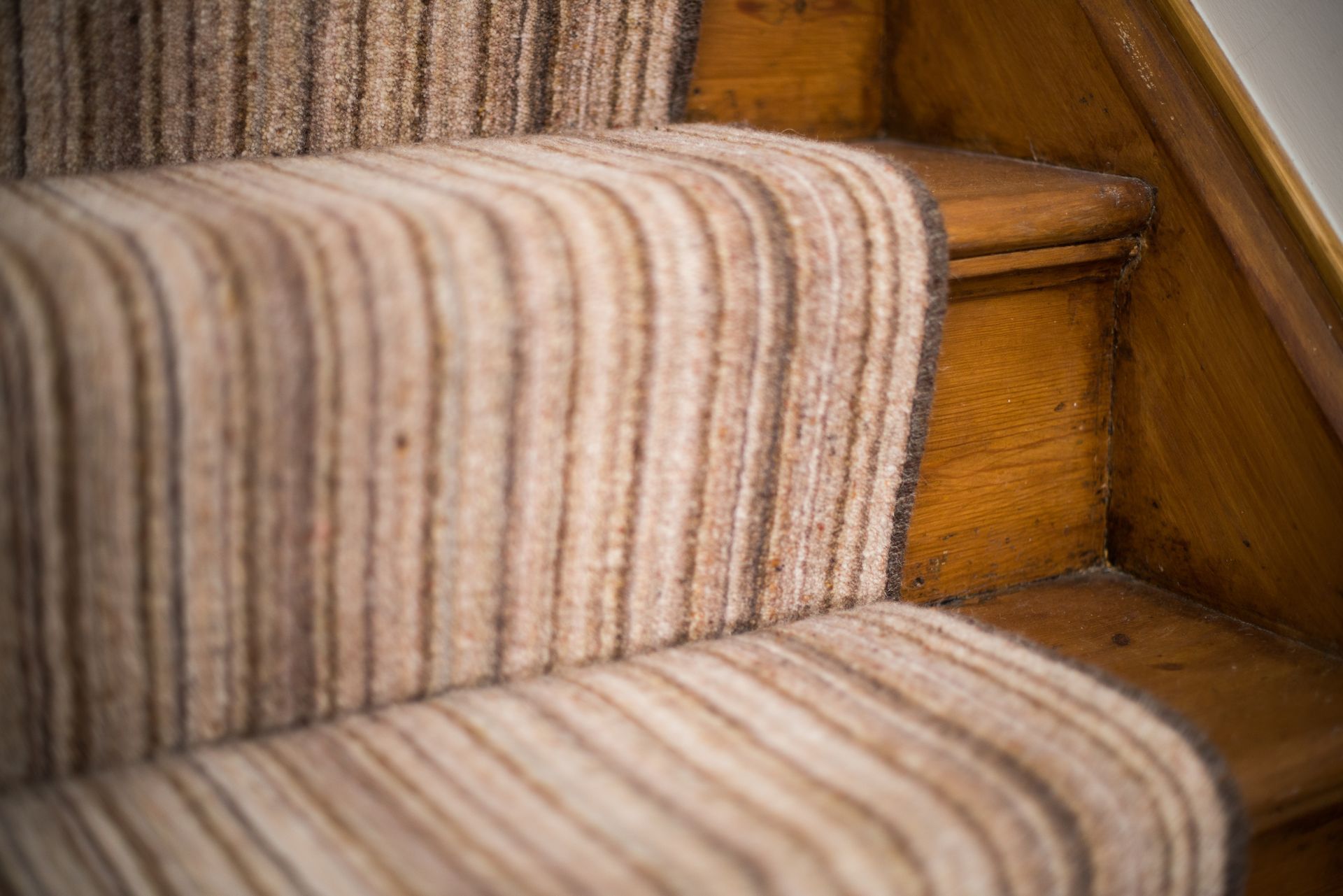 A close up of a staircase with a striped carpet on it.