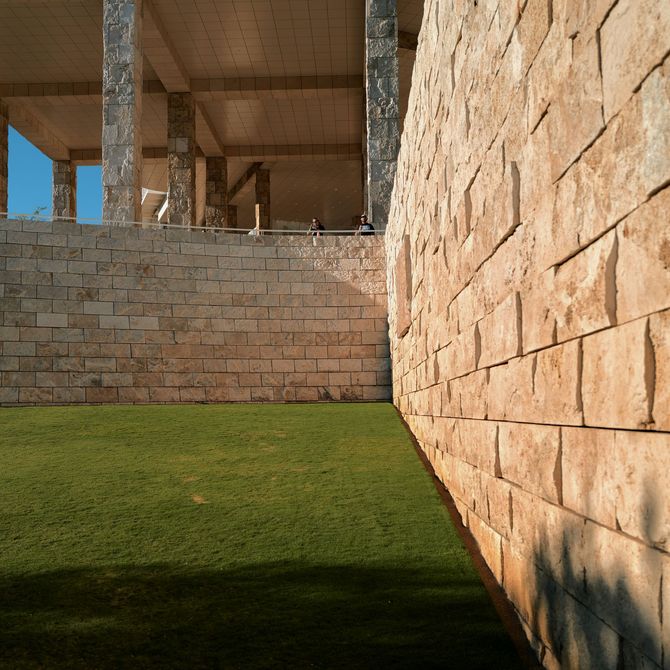 Stone courtyard with green lawn and sunlit stone walls under construction