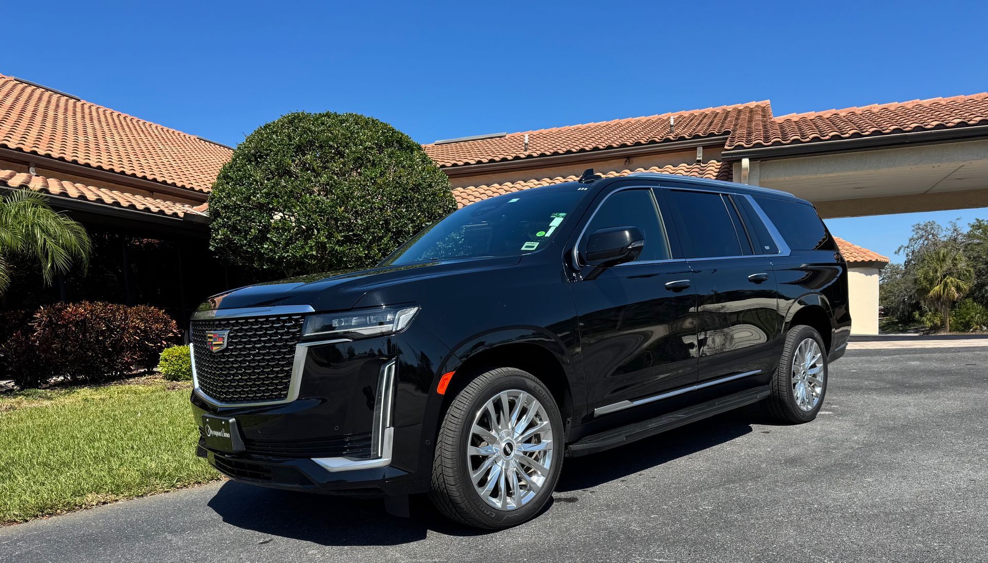 Black GMC Yukon parked in front of a building with a tile roof on a sunny day.