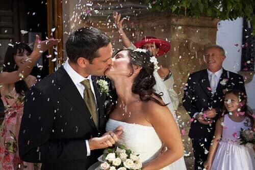 Guests throwing confetti over kissing bride and groom — Corporate Limousine Service in Tampa, FL