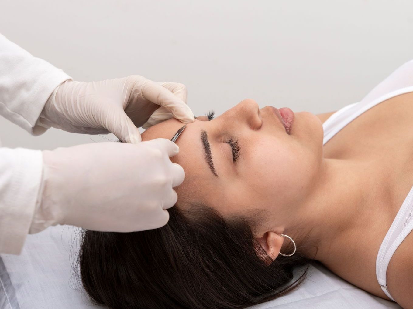 A woman is getting her eyebrows done by a doctor.