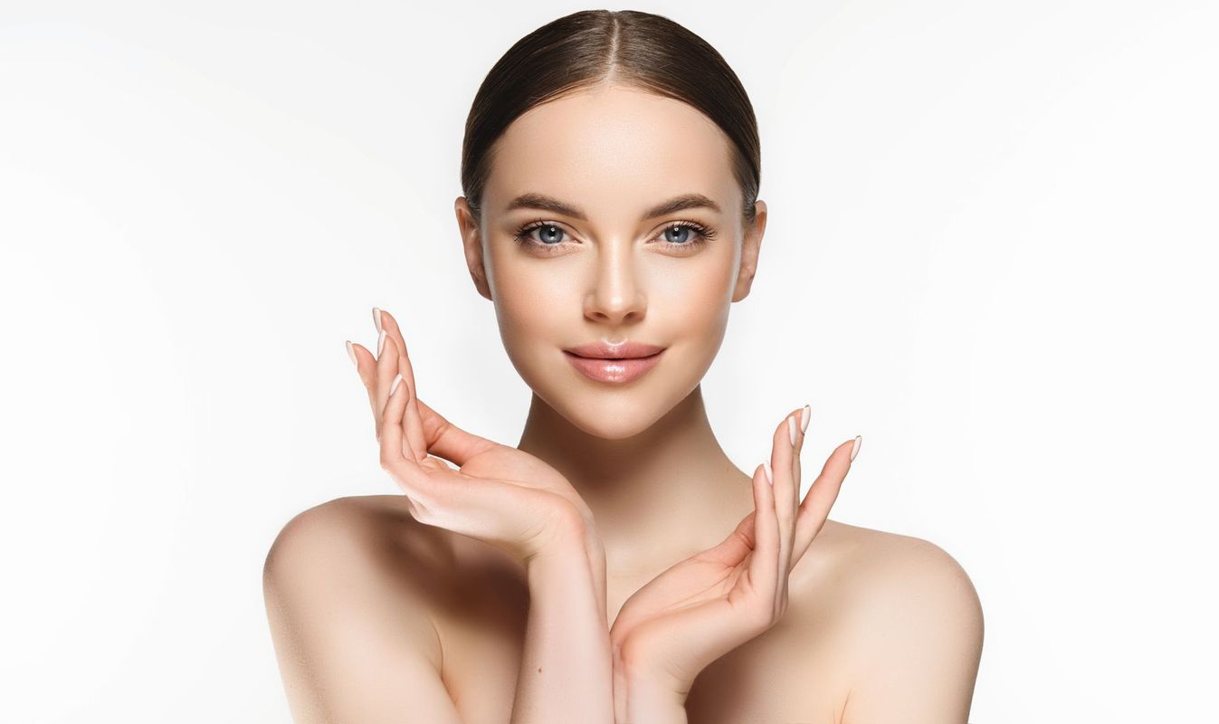A woman is touching her face with her hands and smiling.