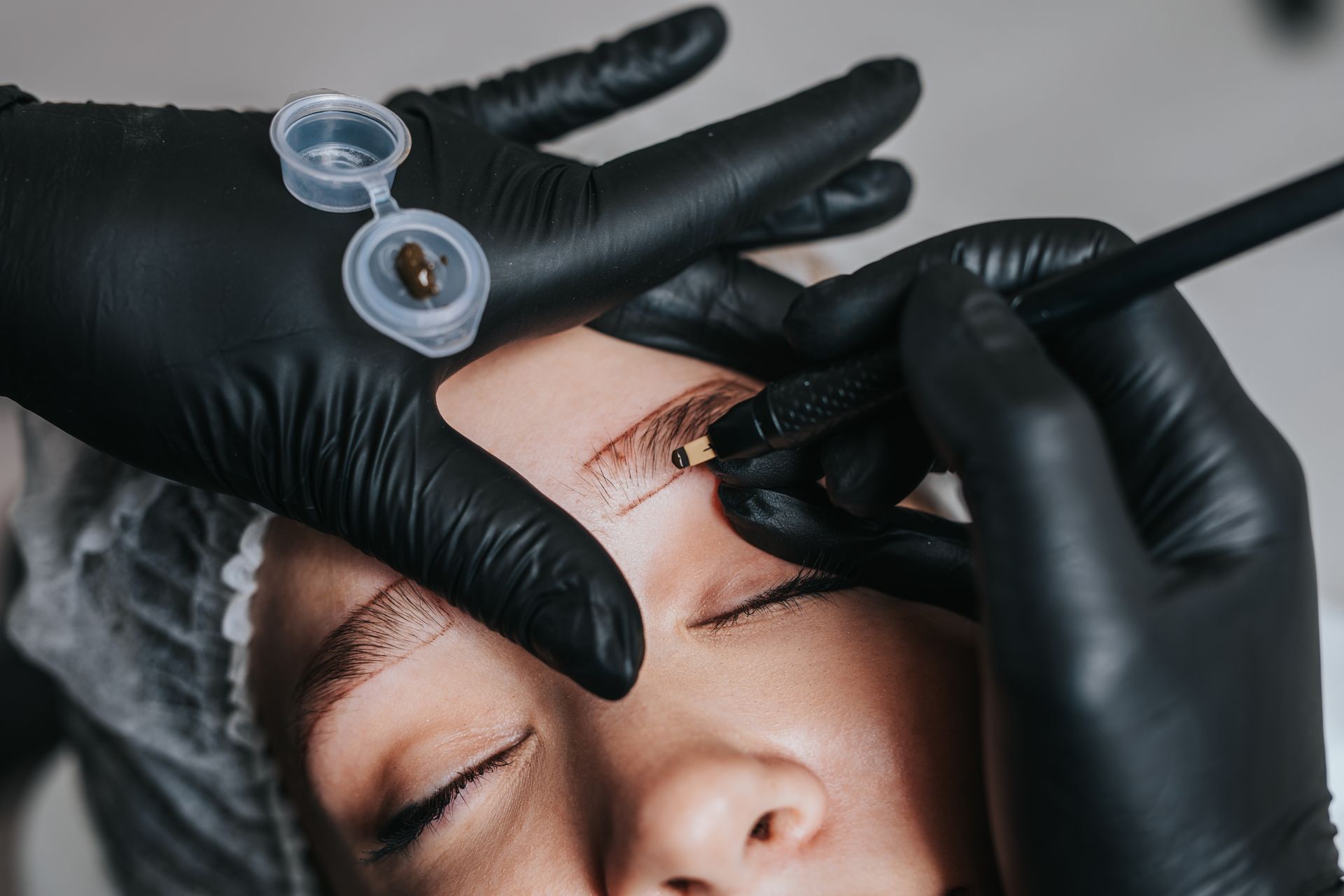 A woman is getting a tattoo on her eyebrows.