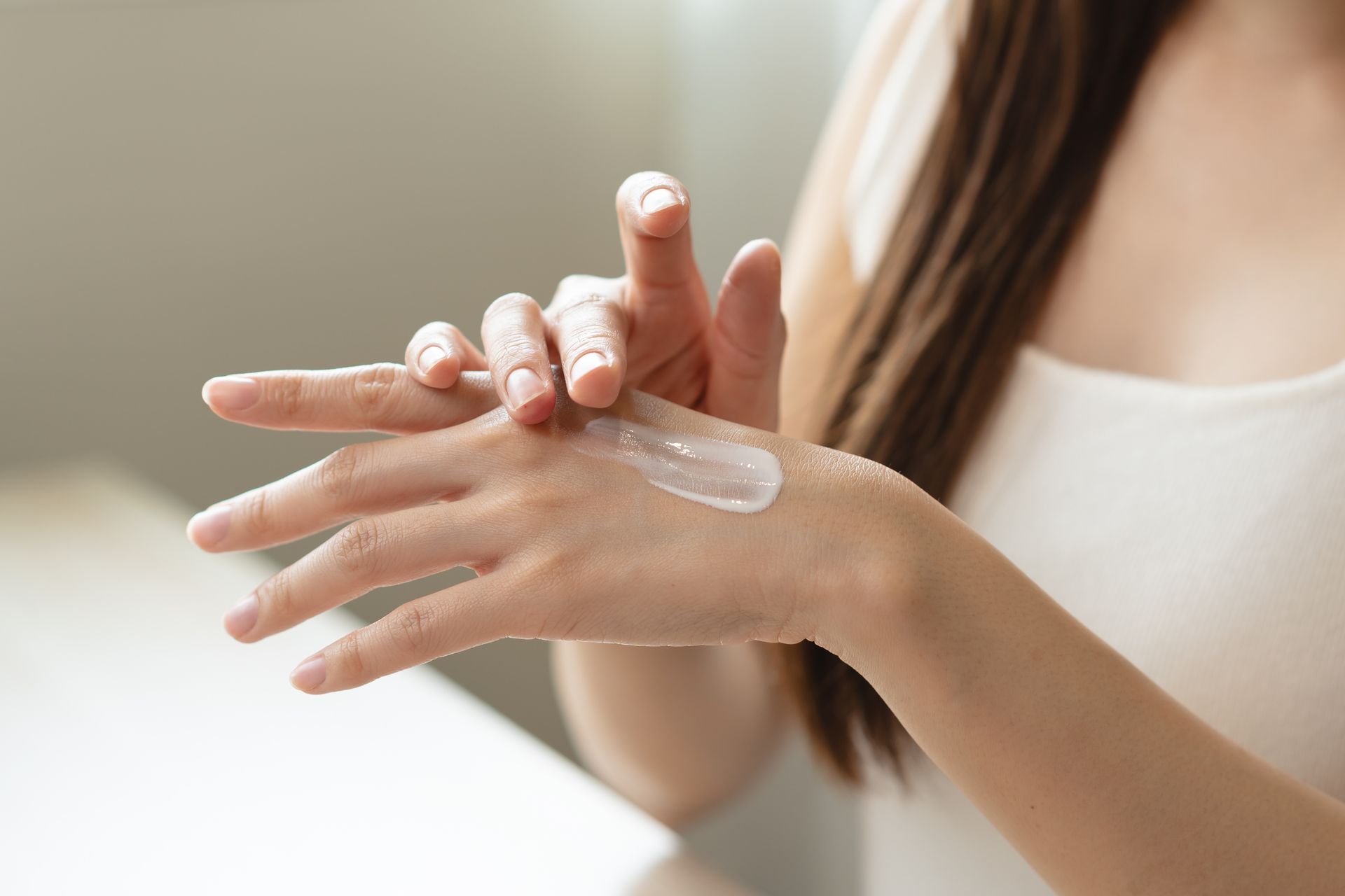 Woman applying hand cream, inside.
